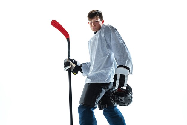 Sério. Jovem jogador de hóquei com o taco na quadra de gelo e fundo branco. Desportista usando equipamento e treino de capacete. Conceito de esporte, estilo de vida saudável, movimento, movimento, ação.