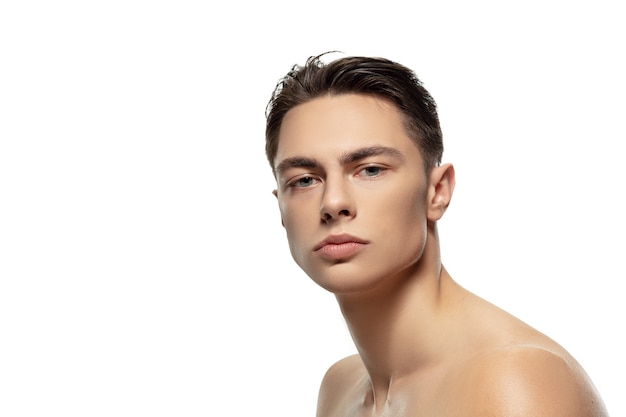 Foto grátis sério. retrato de jovem isolado no fundo branco do estúdio. modelo masculino atraente caucasiano. conceito de moda e beleza, autocuidado, cuidados com o corpo e a pele. rapaz bonito com pele bem cuidada.