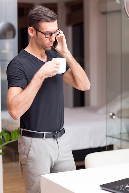 Serious attractive man falando no telefone em casa