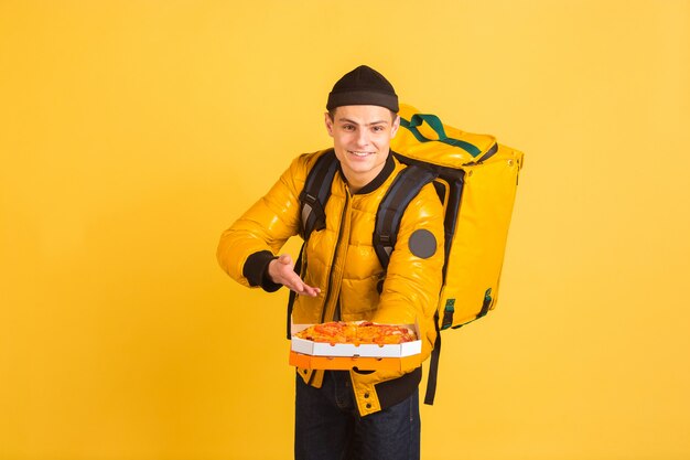 Serviço de entrega sem contato durante a quarentena. Homem entrega comida e sacolas de compras durante o isolamento. Emoções de entregador isolado em amarelo