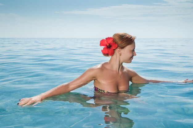 Sexy menina vermelha vestindo biquíni tomando banho no oceano