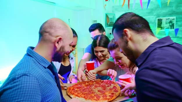 Foto grátis siga a foto de jovem chegando à festa selvagem da faculdade com uma pizza deliciosa.