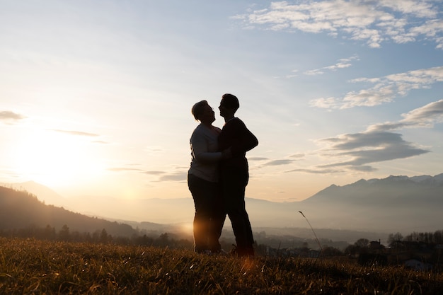 Foto grátis silhueta de família de tiro completo na natureza ao pôr do sol