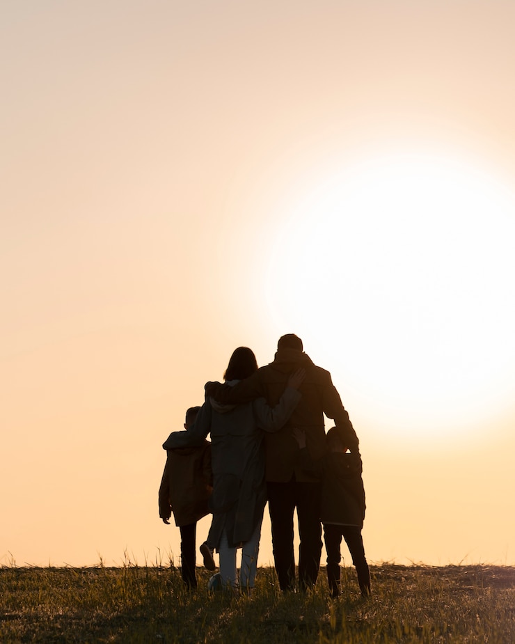 Silhueta de família de tiro completo se divertindo ao pôr do sol