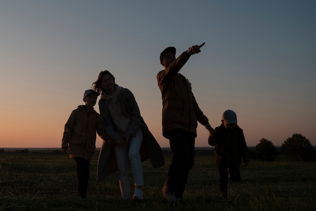 Foto grátis silhueta de família de tiro completo se divertindo ao pôr do sol