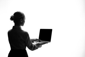 Silhueta de mulher com sombra de vista lateral do laptop iluminada jovem