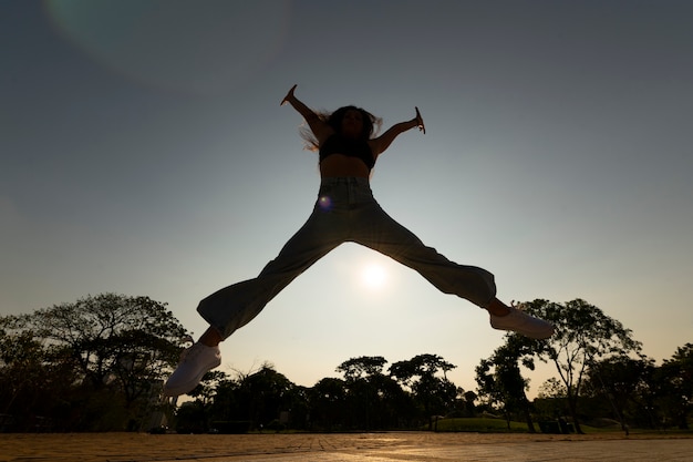 Foto grátis silhueta de mulher de tiro completo pulando ao pôr do sol