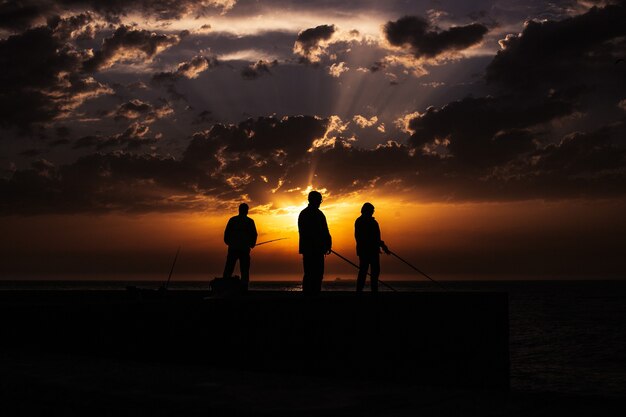 Silhueta de pescador na praia ao pôr do sol