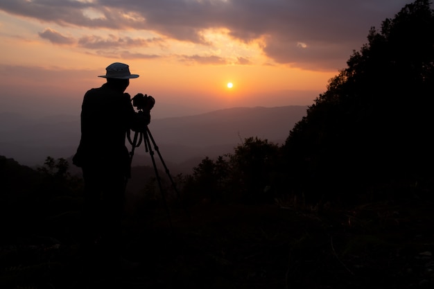 silhueta de um fotógrafo que dispara um pôr do sol nas montanhas