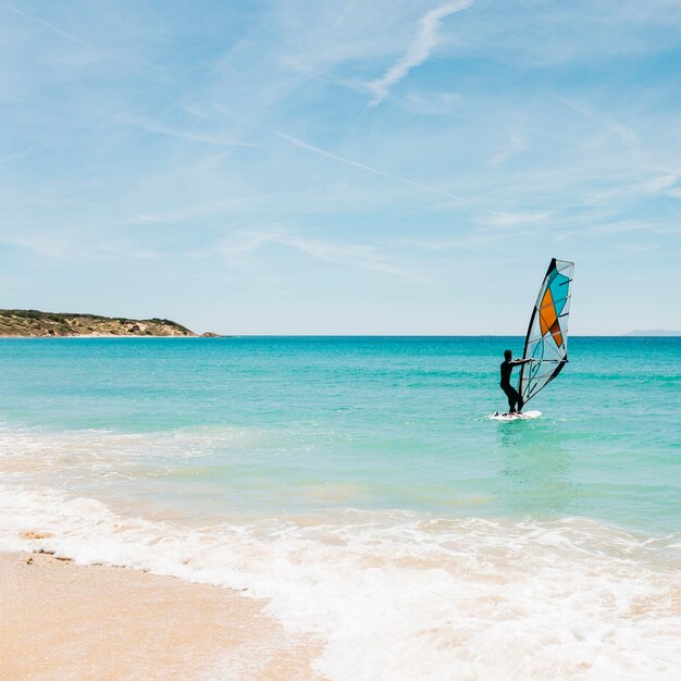 Silhueta de um windsurfer no mar azul.