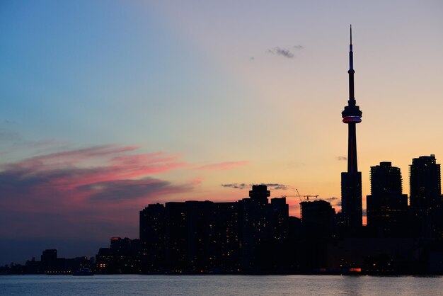 Silhueta do horizonte da cidade de Toronto ao pôr do sol sobre o lago com arranha-céus urbanos.