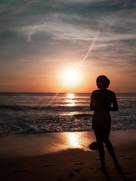 Silhueta do modelo na bela vista do céu ao pôr do sol na praia