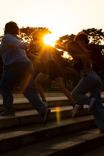 Foto grátis silhuetas de amigos de vista lateral correndo ao pôr do sol