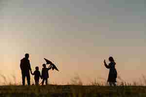 Foto grátis silhuetas de família se divertindo ao pôr do sol plano completo