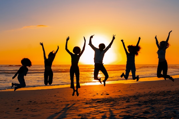 Foto grátis silhuetas de tiro completo de pessoas pulando ao pôr do sol