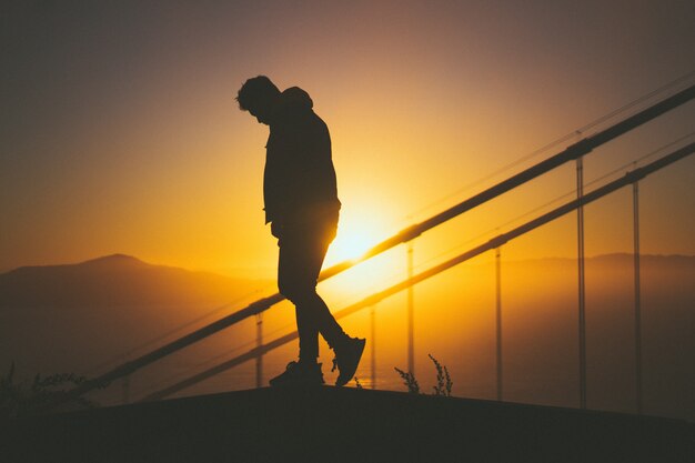 Silueta, jovem, macho, andar, escadaria, atrás de, trilhos escada, com, bonito, pôr do sol, vista