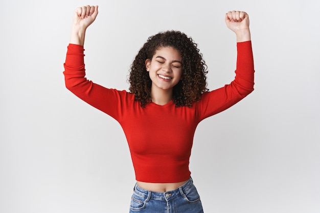 Sim, foi sucesso encantador celebrando jovem garota feliz finalmente alcança a meta conquista ganhar na loteria sentindo alegria levantando os punhos cerrados vitória triunfando olhos fechados dançando sorrindo alegre