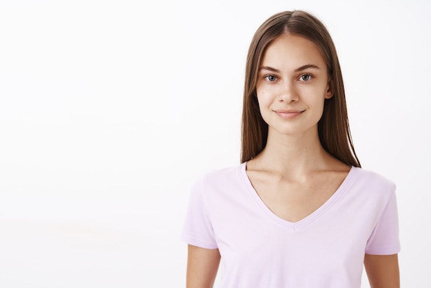 Foto grátis simpática e encantadora morena caucasiana com cabelos longos e pele limpa e saudável, sorrindo com uma expressão educada e fofa, sentindo-se confiante em seus próprios poderes enquanto participa da competição