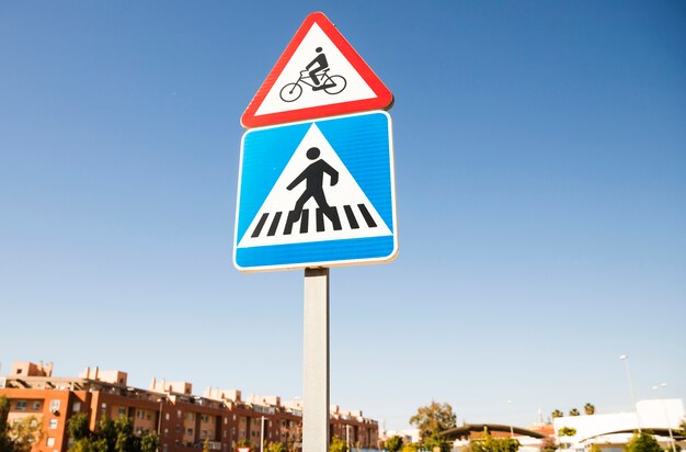 Sinal de aviso de bicicleta triangular sobre o sinal de estrada de passagem para pedestres quadrado na cidade