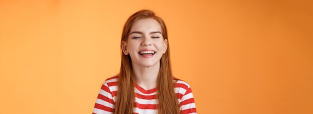 Foto grátis sincera e feliz ruiva carismática sorrindo de olhos fechados desfruta de raios de sol quentes de verão rindo alegre