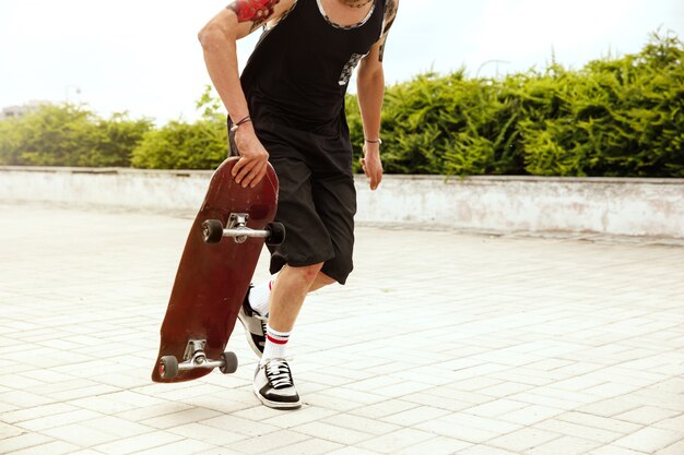 Skatista fazendo uma manobra na rua da cidade em dia nublado. Jovem de tênis e boné e longboard no asfalto. Conceito de atividade de lazer, esporte, radical, hobby e movimento.
