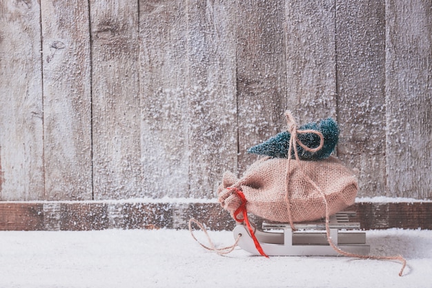 Foto grátis sledge com um saco de presentes e um pinheiro no topo