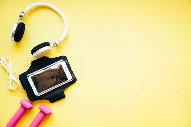 Smartphone com fones de ouvido e halteres