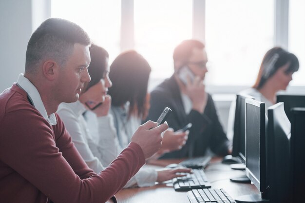 Smartphone de cor preta. Jovens que trabalham no call center. Novos negócios estão chegando