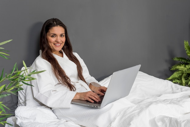 Smiley feminino na cama com o laptop