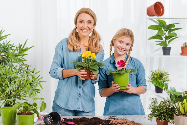Foto grátis smiley filha e mãe segurando o vaso de flores