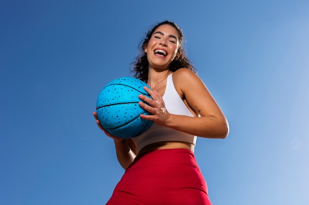 Foto grátis smiley fit mulher segurando a bola de baixo ângulo