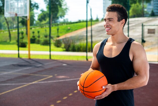 Smiley homem segurando uma bola na quadra de basquete