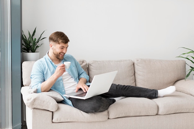 Smiley homem tomando café e usando o laptop