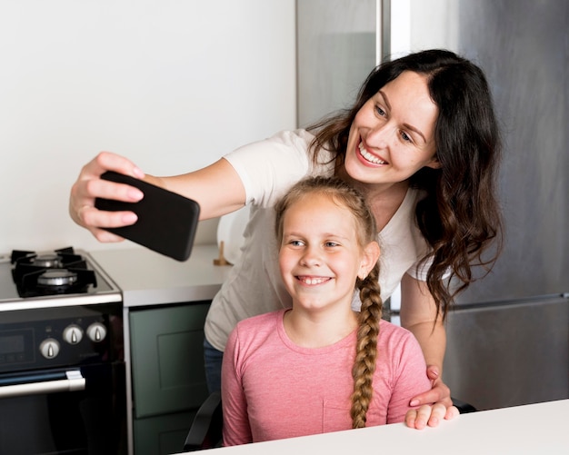 Foto grátis smiley mãe e menina tomando selfie