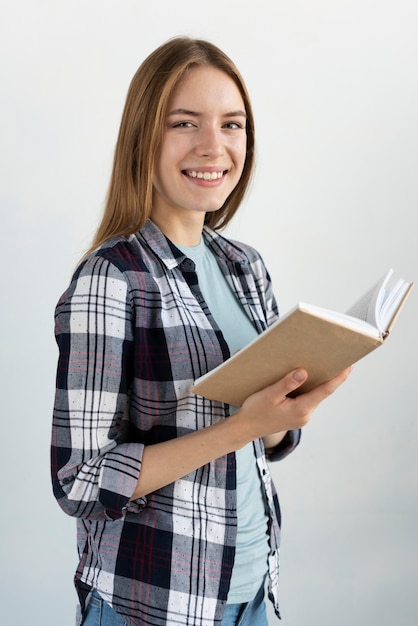 Foto grátis smiley mulher segurando um livro enquanto olha para a câmera