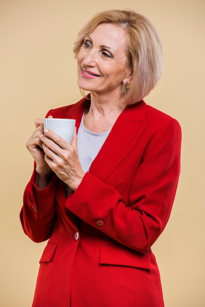 Smiley mulher sênior, olhando para longe enquanto segura uma xícara de café