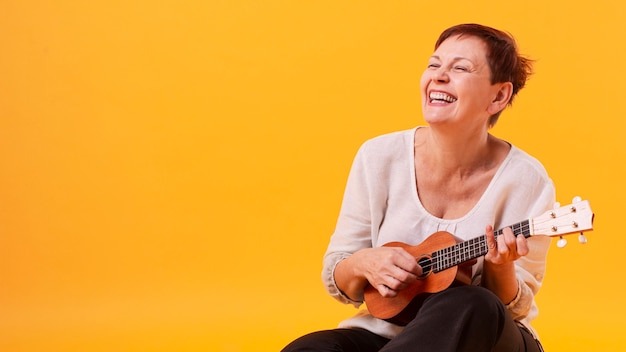 Smiley mulher sênior tocando violão
