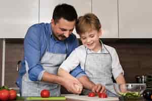 Foto grátis smiley pai e filho cortar legumes