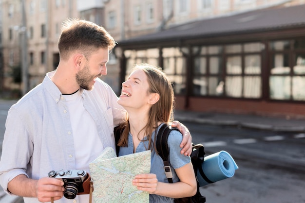 Foto grátis smiley turista casal ao ar livre com mapa e câmera