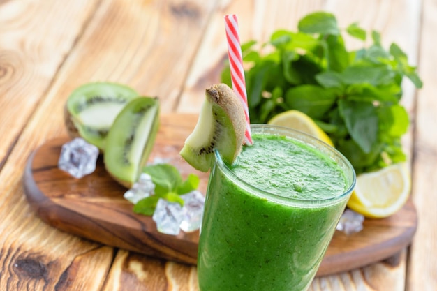 Smoothie de frutas e vegetais verdes em uma mesa de madeira