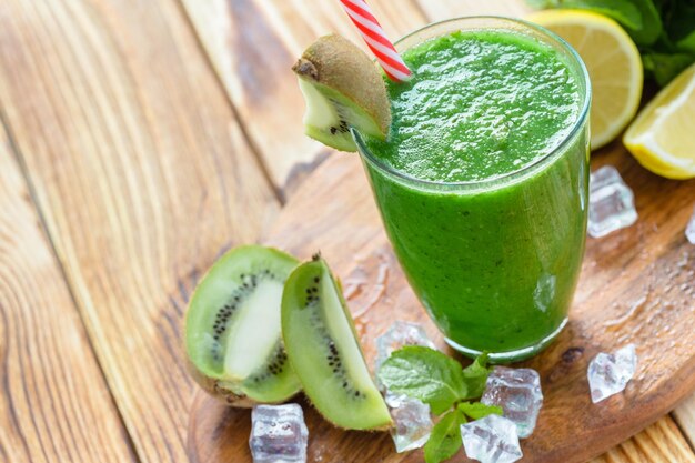 Smoothie de frutas e vegetais verdes em uma mesa de madeira