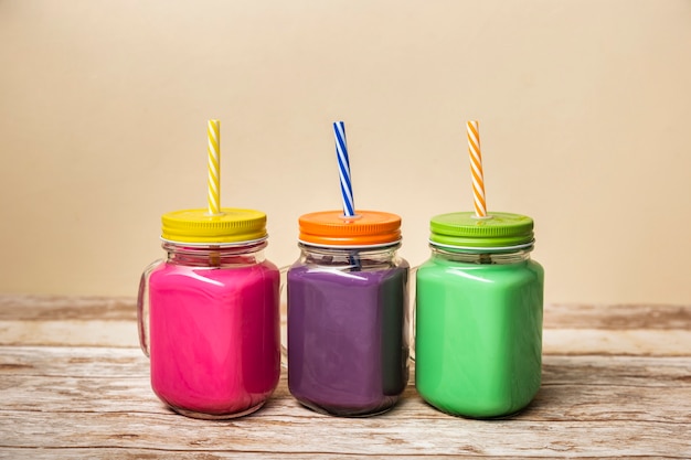 Foto grátis smoothies coloridos de vista frontal em frascos
