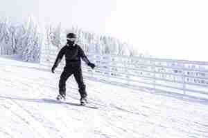 Foto grátis snowboarder em movimento descendo a colina em um resort nas montanhas