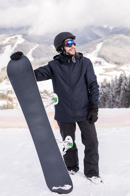 Snowboarder segurar snowboard no topo da colina perto do retrato, montanhas de neve snowboard nas encostas.