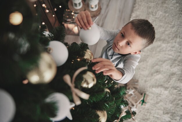 Sobrecarga de menino de pijama preparando uma árvore de Natal