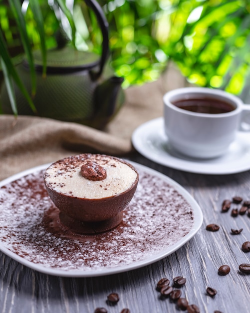 Sobremesa de café vista lateral com creme em grãos de café de xícara de chocolate e xícara de chá na mesa