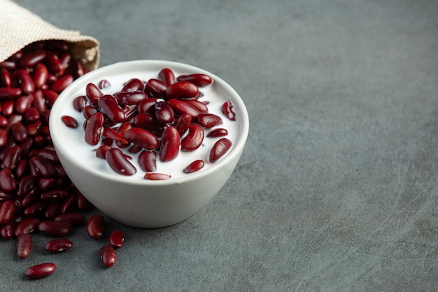 Sobremesa de leite de coco de feijão vermelho em uma tigela branca colocada ao lado do saco de feijão vermelho