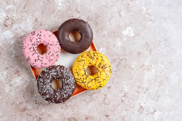 Sobremesas variadas com cobertura de chocolate, glacê rosa e granulado.