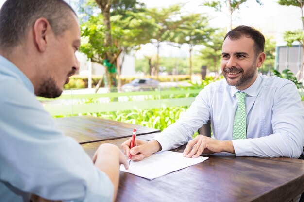 Sócios de negócio bem sucedidos alegres que discutem o contrato