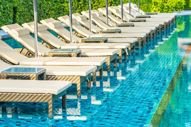 Sofá guarda-chuva e cadeira em torno da piscina ao ar livre no hotel resort para férias